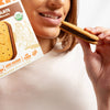 Woman holding a chocolate biscuit and a box of the same biscuit on a white background