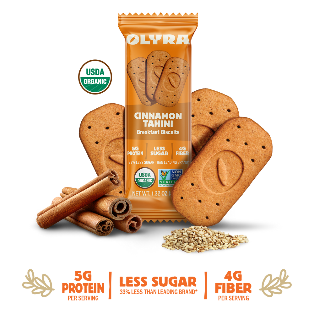 Olyra Cinnamon Tahini breakfast biscuits with packaging, cinnamon sticks, and seeds on a white background.
