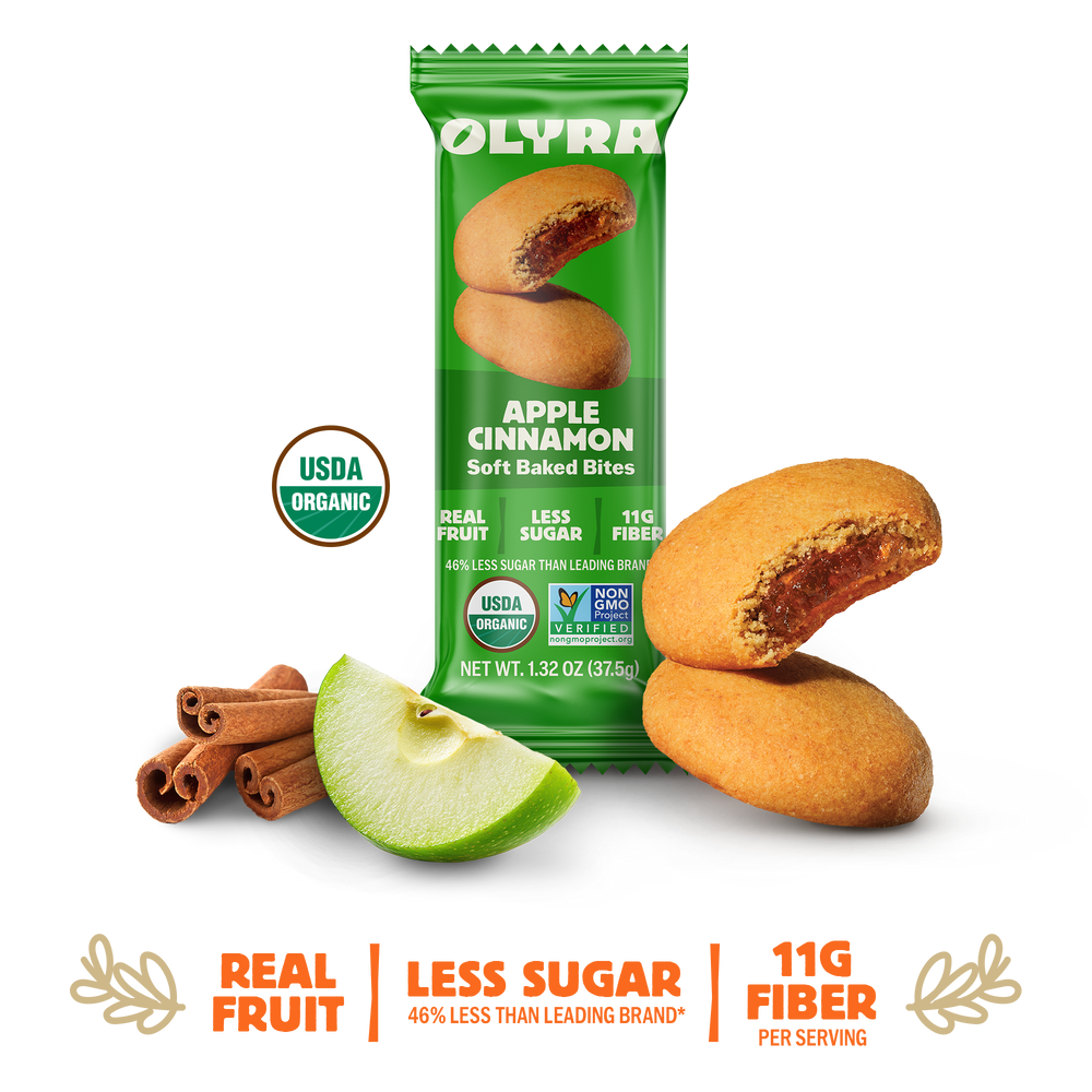 Olyra Apple Cinnamon soft baked bites packaging with cookies, apple, and cinnamon sticks on a white background.