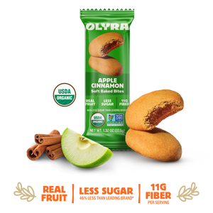 Olyra Apple Cinnamon soft baked bites packaging with cookies, apple, and cinnamon sticks on a white background.