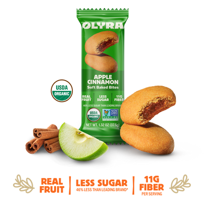 Olyra Apple Cinnamon soft baked bites packaging with cookies, apple, and cinnamon sticks on a white background.