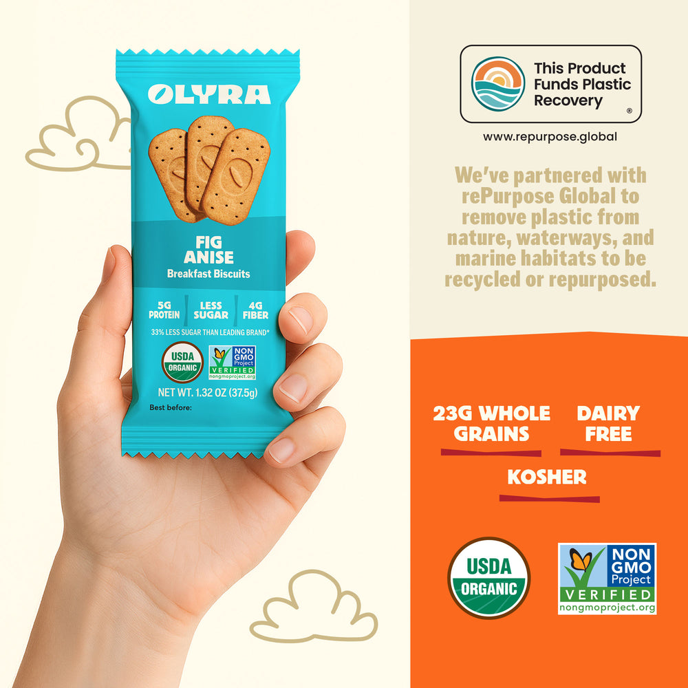 Olyra Fig Anise breakfast biscuits package held by a hand with product details on an orange background.