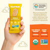 Hand holding a yellow Olyra vanilla crème breakfast cookies package with product details on an orange background.