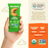 Olyra Apple Cinnamon soft baked bites packaging held in a hand with product details on an orange background.