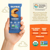 Olyra blueberry soft baked bites package held by a hand with product details on an orange background.