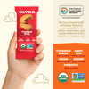 Olyra pumpkin spice soft baked bites packaging held by a hand with product details on an orange background.