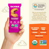 Purple Olyra raspberry soft baked bites package held by a hand with product details on an orange background.