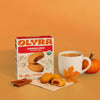 Olyra pumpkin spice soft baked mix with cookies, a mug of coffee, and a pumpkin on an orange background