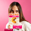 Person holding an Olyra strawberry soft baked bites box against a pink background